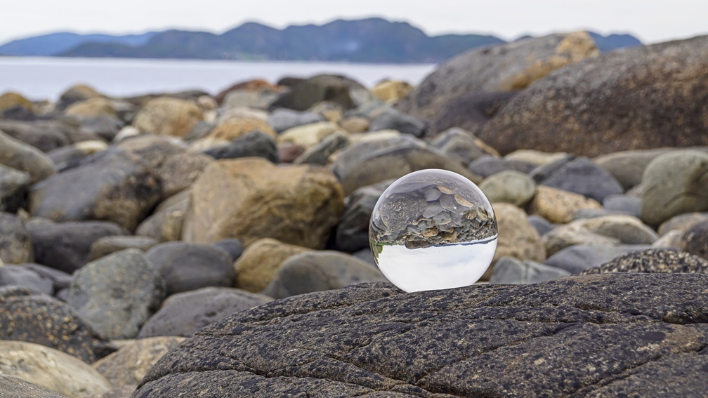 Glaskugel an einem steinigen Strand