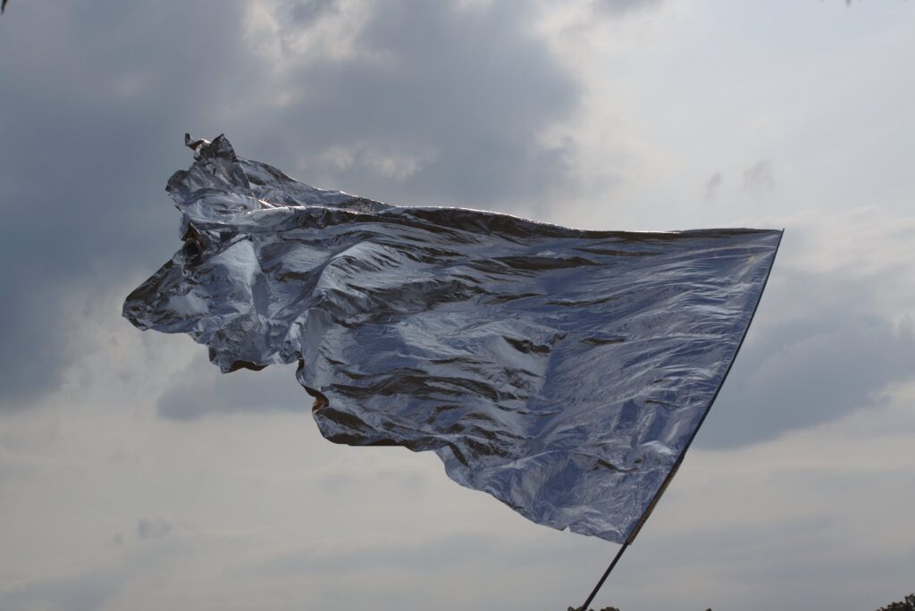 Eine silberne Fahne weht vor einem wolkigen Himmel.